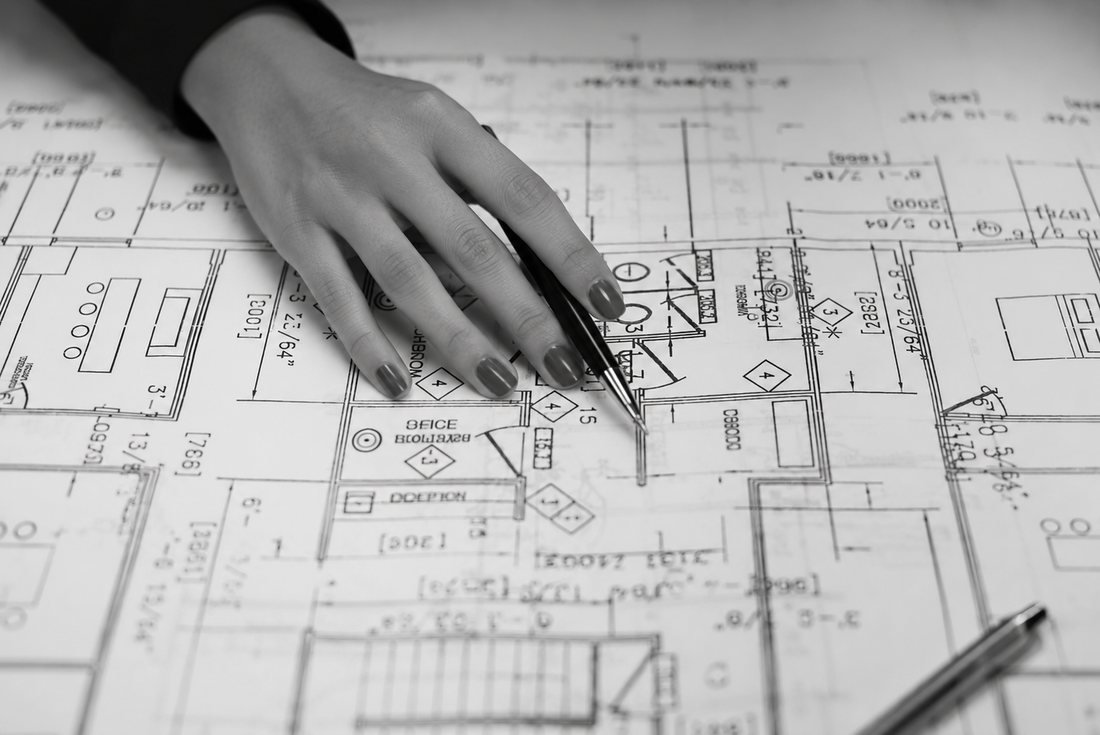 Planta de layout corporativo sobre a mesa, com um compasso apoiado no desenho.